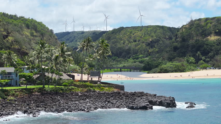 Waimea Valley panorama on Oahu North shore USA travel. Cinematic aerial Waimea Bay Beach on sunny summer day. People enjoy vacation on beautiful sandy beach. Scenic nature landscape of Hawaii island