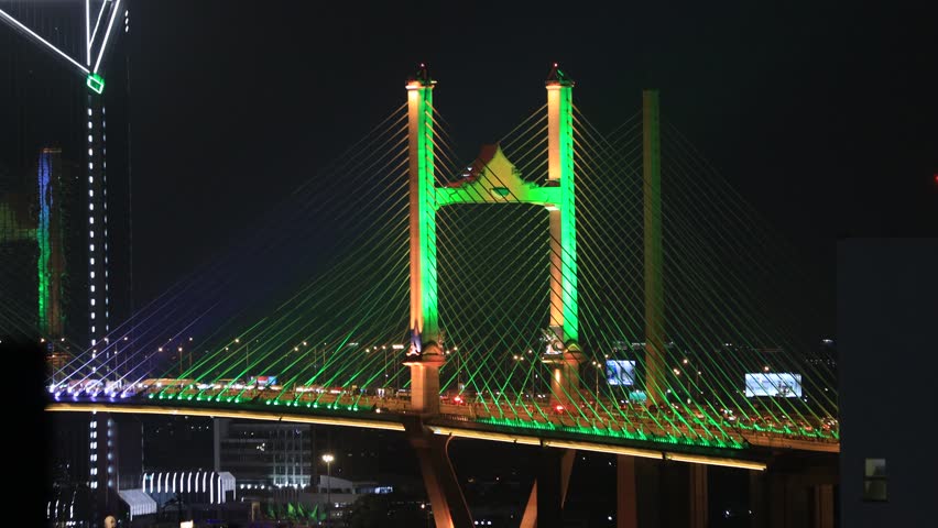 Blurred video background of colorful night lights. Beautiful bokeh is created along the bridge over the river and there is heavy traffic.
