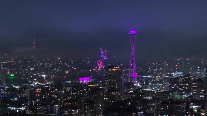 Drone show at observation tower illuminated at night. Cinematic landmark on New Year eve. Night celebration on New Year 2024. Beautiful Seattle city at night. Scenic night aerial of Seattle downtown