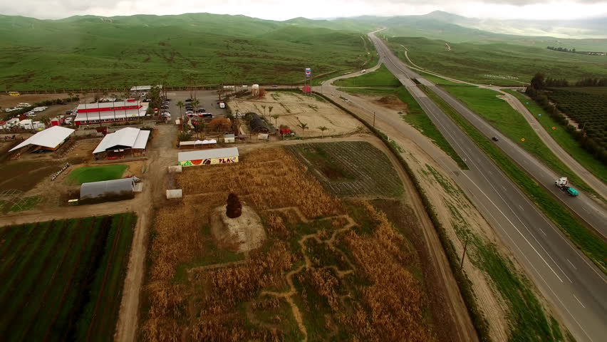 Aerial: Drone Forward Shot Of Structures And Vehicles Amidst Green Hills - Bakersfield, California