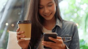 Young asian beautiful woman using smart phone in coffee shop cafe, typing write message on mobile, online shopping, transfer payment, internet banking