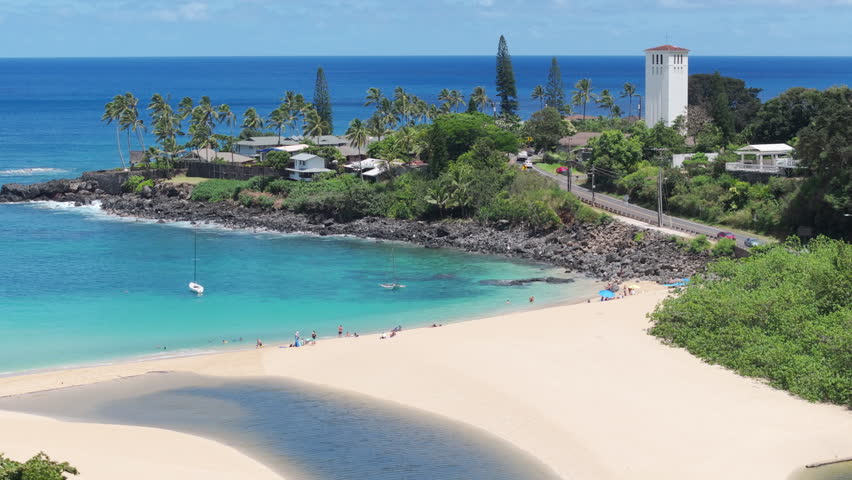 Blue lagoon with clear blue water at Waimea beach on Oahu island. Cinematic aerial Waimea Bay Beach on sunny summer day. People enjoying vacation on beautiful sandy beach. Scenic nature Hawaii island