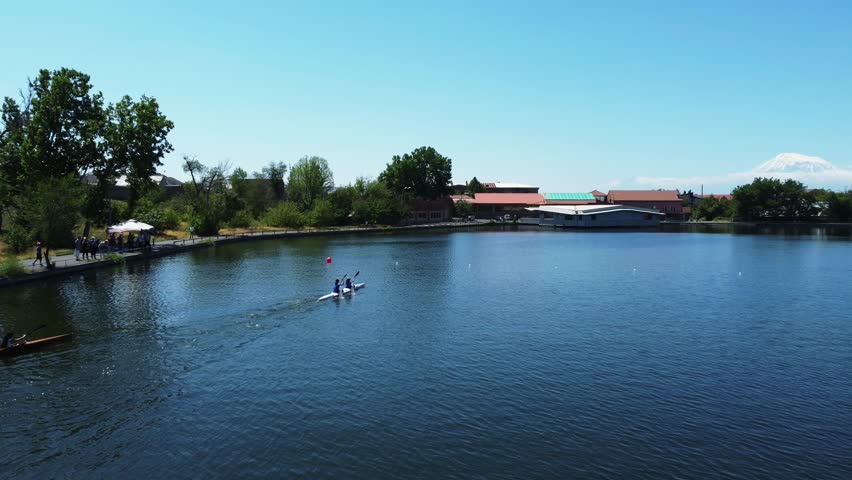 Top view of rowing competition as girls paddle kayak on lake, swimming to finish line. Rowing training session captured on the serene waters.