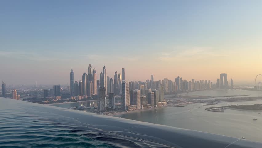 Aerial view of Dubai Palm Jumeirah island, United Arab Emirates. Tourists relaxing in AURA sky pool bar, the world