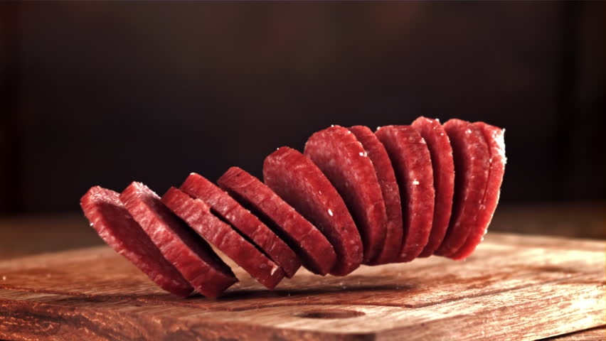 Pieces of salami fall onto a wooden board. Filmed on a high-speed camera at 1000 fps. High quality FullHD footage