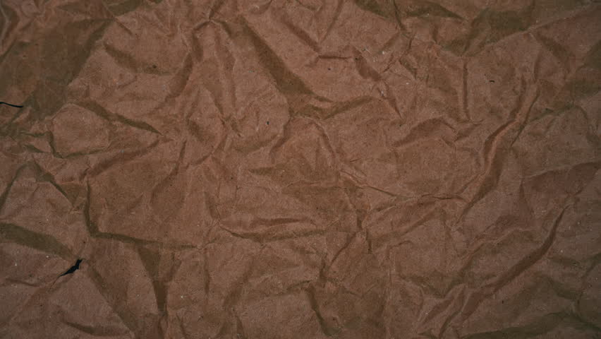 Animation of folding craft paper, freeze frame on green screen, chromakey. Transition from craft paper to green background.