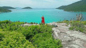 Girl red dress standing on the shore with crystalline turquoise sea in Arraial do Cabo, Rio de janeiro, Brazil. Aerial drone view. - Powered by Shutterstock - Get 15% off with code: PIKWIZARD15