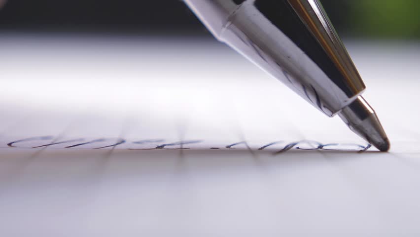 Ballpoint pen writes on a sheet of paper, extreme close-up shot.
