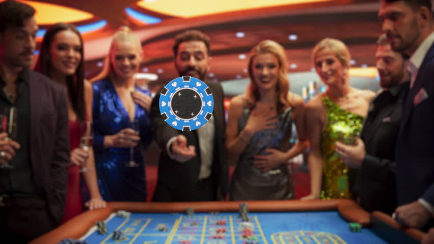 Successful Men and Women Partying in a Luxurious Casino. Young People Gambling at a Roulette Table, Putting High Stakes Bets. Slow Motion Footage of a Person Tossing a Blue Chip with a Placeholder
