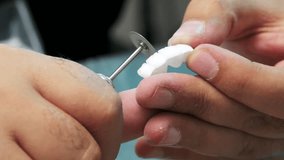 A meticulous close-up of porcelain tooth refinement in a dental lab