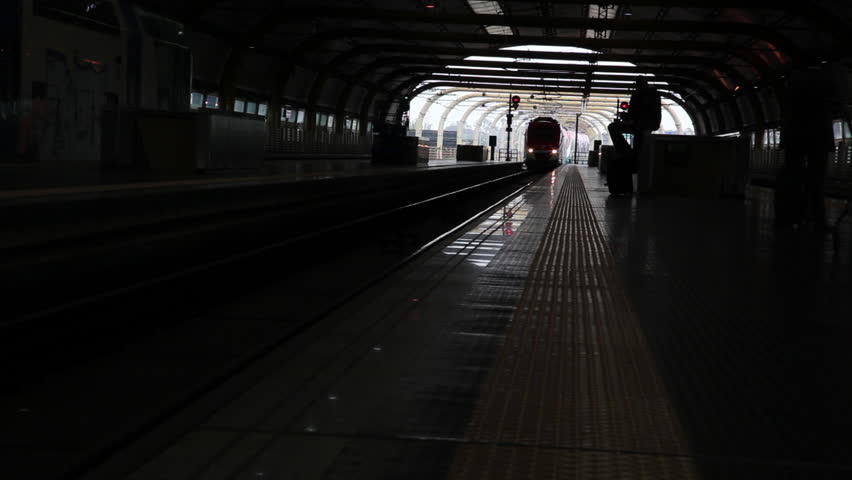 A train pulls up to a platform, the headlights going out of the frame. A