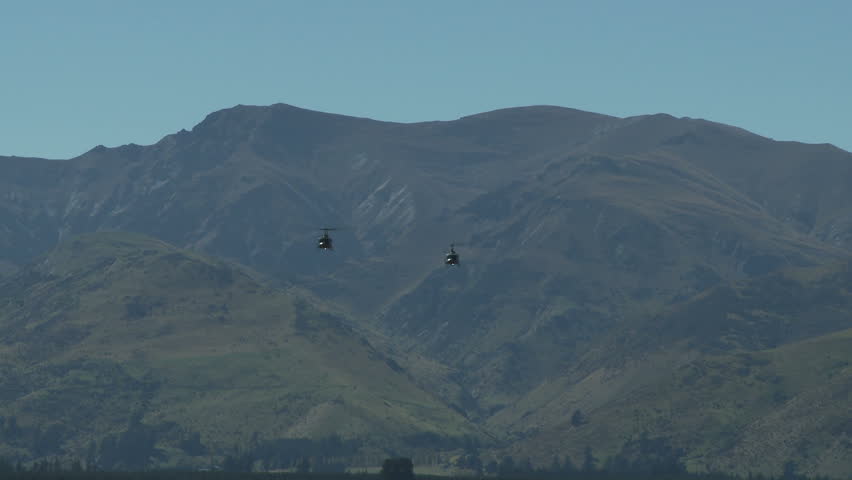Two military helicopters in flight heading towards camera