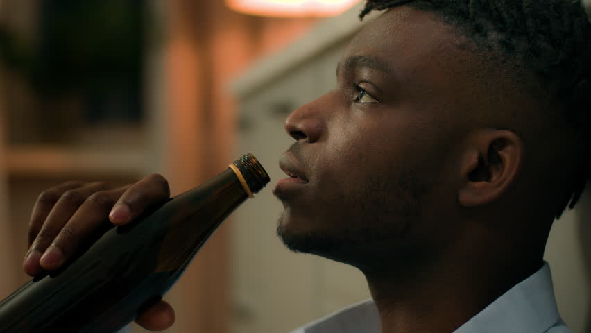 Addicted upset drunk African American depressed stress man drinking alcohol sad suffer problem drink beer with bottle ethnic guy biracial male addiction stressed mental worry bad habit home kitchen Royalty-Free Stock Footage #3442714467