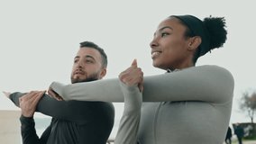 Multiethnic couple stretching together outdoors, showing joy and fitness lifestyle by the water. Active, healthy living and exercise concept. - Powered by Shutterstock - Get 15% off with code: PIKWIZARD15