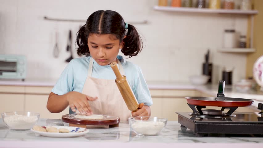 Happy Girl Kid looking at camera by showing chapati while doing chapati at kitchen - concept of childhood fun, playful activities and hobbies Royalty-Free Stock Footage #3442747047