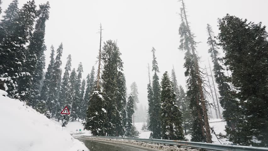 Driving On Curved Road During Snowfall In Winter. Gulmarg, Jammu And Kashmir, India. low angle, slow motion Royalty-Free Stock Footage #3442798837