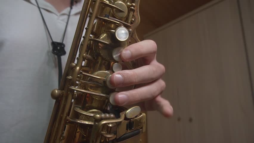 A student in a white T-shirt rehearses the saxophone jazz improvisations at home Royalty-Free Stock Footage #3442810529