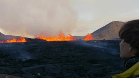 Volcanic eruption in Iceland after earthquake. Young brown hair man watches boiling lava flows from the crater. - Powered by Shutterstock - Get 15% off with code: PIKWIZARD15