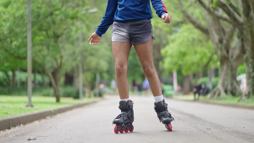 Portrait of queer man enjoying skating with roller skates and having fun at city park. Happy Genderqueer lgbt black man

