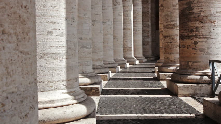 Inside the colonnade, pillars curve away from the camera on a sunny day in