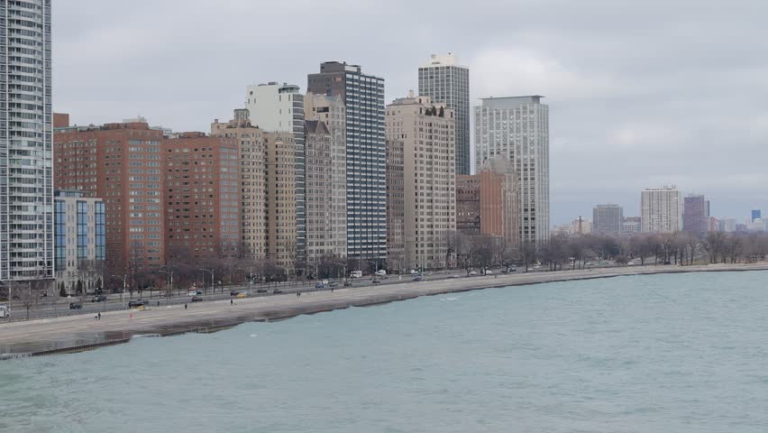 Drone shot of beachfront apartment buildings and Lake Shore Drive expressway alongside shoreline of Lake Michigan, Chicago, Illinois, United States