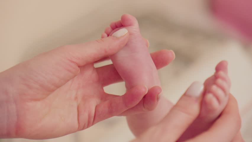 Small baby feet are cradled in loving hands, highlighting the innocence and serenity of infant sleep. Royalty-Free Stock Footage #3442941951