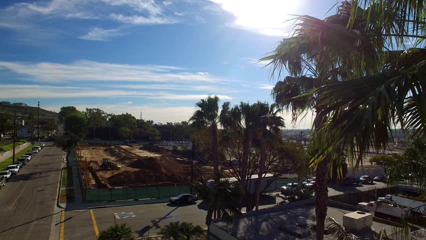 Aerial: Drone Upward Shot Of Cars Parked On Roads In City Under Cloudy Sky During Sunny Day - Long Beach, California