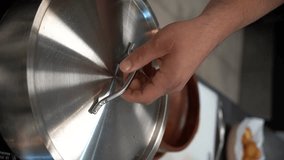 the chef opens the lid of the pan with the prepared meat cut into cubes inside and adds hot red chili pepper, cut in half, to the meat. vertical video - Powered by Shutterstock - Get 15% off with code: PIKWIZARD15