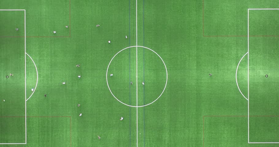 Amateur soccer field and game. People excersising and playing the game of football. Aerial top down view on the field. Green grass and sports.