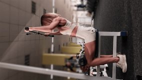Vertical video: Beautiful sporty young woman training back muscles in gym. Focused video