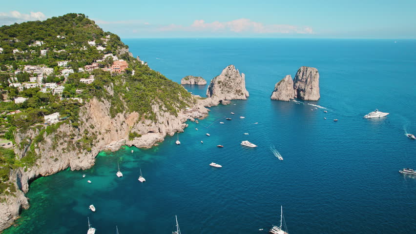 Capri coastline shines with Mediterranean nature under the summer sun. The high cliffs Faraglioni of Island and deep blue sea in Italy. Royalty-Free Stock Footage #3443096643