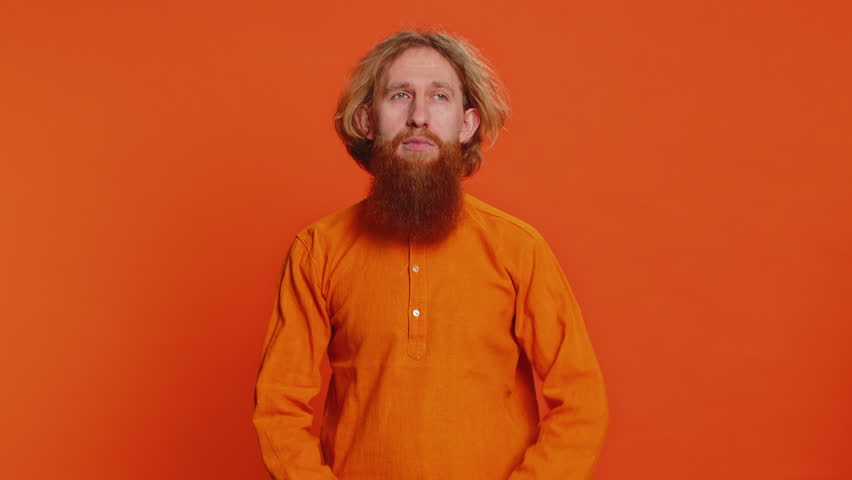 Caucasian man photographer gesturing picture frame with hands, looks through fingers and focusing on interesting moment, imitating zoom and cropping nice image. Young guy isolated on orange background