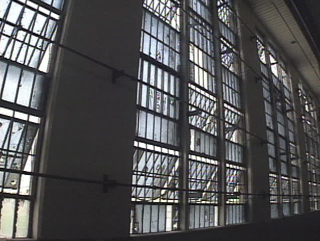 Pan from windows to a row of cells inside a prison. 
