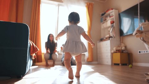 baby runs to his parents for first steps. happy family child - dream concept. little daughter takes his first steps towards his family at window of the house. Cute baby learning to lifestyle walk Vídeo Stock