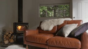 Dolly shot of cozy forest cabin with leather comfortable sofa at fireplace. Modern interior of country house in green forest. Comfortable pillows on brown coach. Small home interior design living room - Powered by Shutterstock - Get 15% off with code: PIKWIZARD15