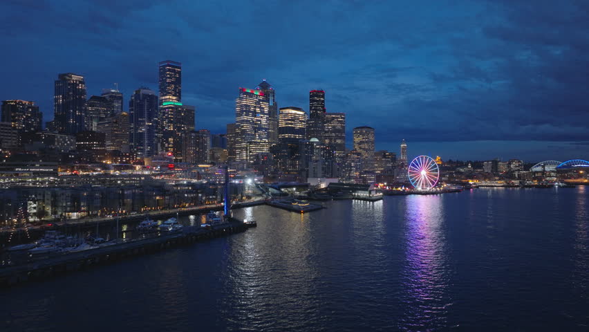 Downtown Seattle at dark winter night light. 4K b roll drone shot of cityscape night scene. Illuminated night city USA. Aerial panorama of seafront and financial district skyscrapers and buildings