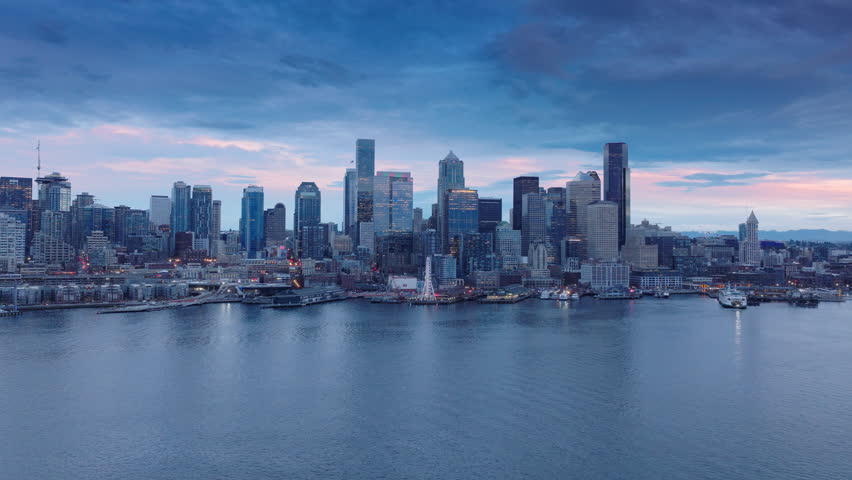 City lights in purple sunset sky Washington. Downtown Seattle at pink sunset. Scenic Seattle skyline panorama. Aerial view downtown at night scene.Beautiful urban landscape of coastal bay city at dusk