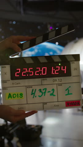 Vertical Screen: Female Directing a Movie Sequence with an Astronaut in Open Space. Studio with Virtual Production Screen Showing Planet Earth and a Practical Effect Mock Up of a Satellite Royalty-Free Stock Footage #3443332467