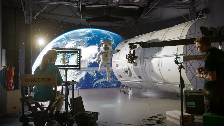 Studio Production Working on an Advertising Campaign with an Astronaut Fixing a Satellite in Outer Space. Behind the Scenes with an Actor Floating on a Rope with a Digital Screen Showing Planet Earth Royalty-Free Stock Footage #3443334529