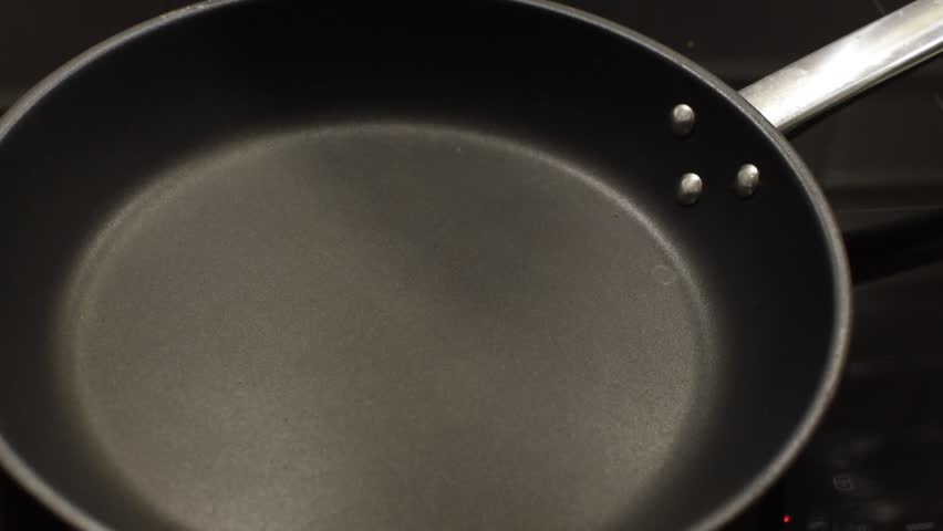 A piece of butter melts in a hot frying pan.