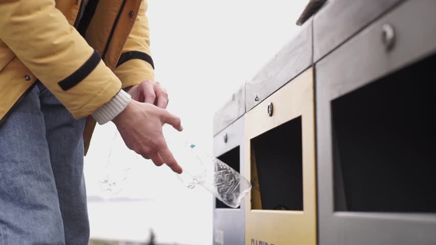 A man's hand throws a container for recycling plastic bottles, garbage sorting, trash can