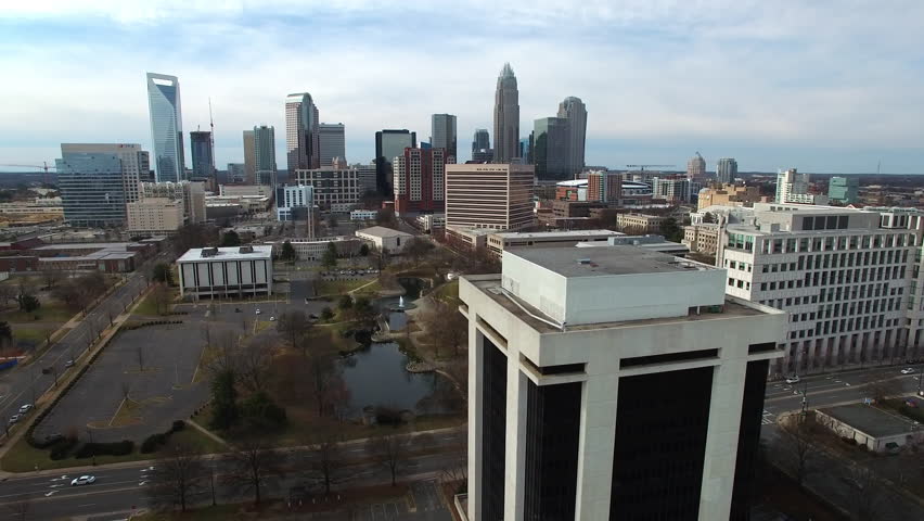 Aerial Tilt Down Shot Of Modern Buildings In Downtown District By Rv Bus In Parking Lot - Charlotte, North Carolina