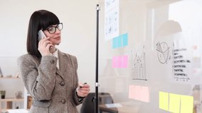 Confident caucasian woman in formal wear and glasses solving business issues having phone call while standing at company boardroom. Concept of modern technology and busy people. - Powered by Shutterstock - Get 15% off with code: PIKWIZARD15