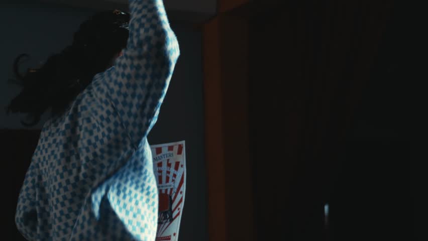 Side view of a woman passionately singing with a microphone in a dimly lit setting during the night