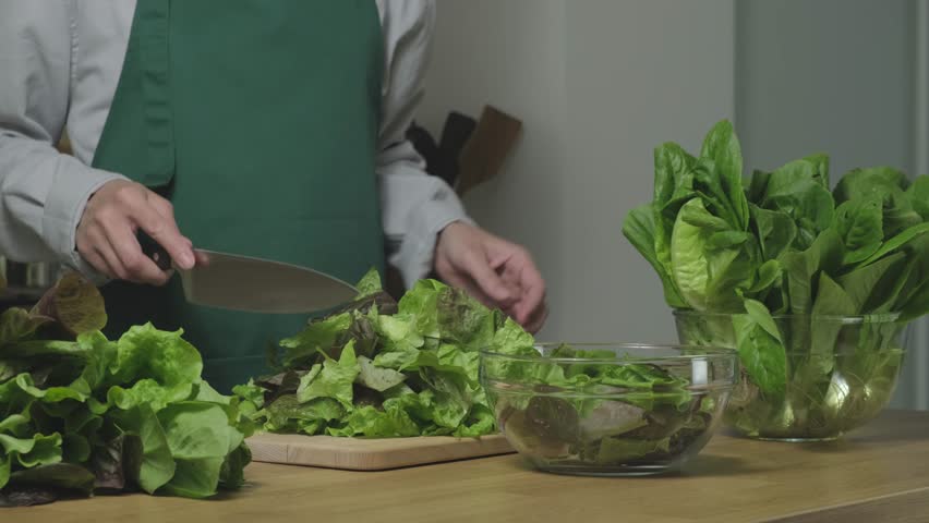 Vegetarian salad with greens. Cutting romaine lettuce green leaves on the home kitchen. Concept of Healthy food, keto diet, vegetarianism, veganism. Preparing vegetarian salad