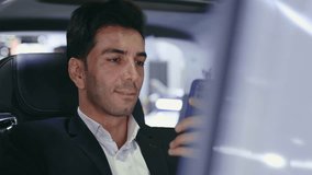 Happy and Smiling Businessman Using Cellphone While Sitting in Passenger Seat of Car. Young, Cheerful Guy Watching Videos on Cellphone While in Automobile. Car and Technology Concept