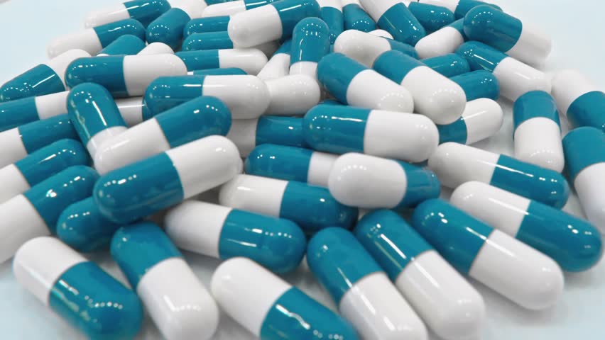 Professional production of food supplements in the form of capsules. Blue and white preparations. Vitamins and capsules on a medical background: we care about your well-being. The Medicines Vitamins