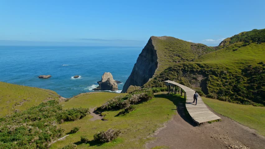 Panoramic orbit flyover of a person walking on the pier of souls in Cucao, Chiloe. Lone traveler in chile