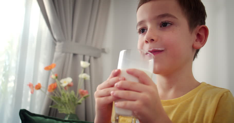 Cute Handsome child drinking milk.Healthy eating a child eating breakfast kid dream concept. Funny little boy in kitchen drinks yogurt milk and licks her lips.Positive kid smiling having breakfast. 4K Royalty-Free Stock Footage #3443832777