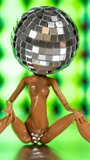A sparkling doll with a discoball head dances spinning on a record turntable in vertical